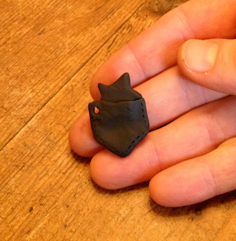 A very small pocket with a star in it, sculpted from black plastercine