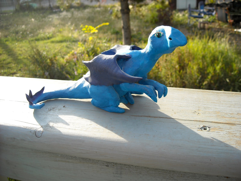 A light and dark blue acrylic painted clay dragon