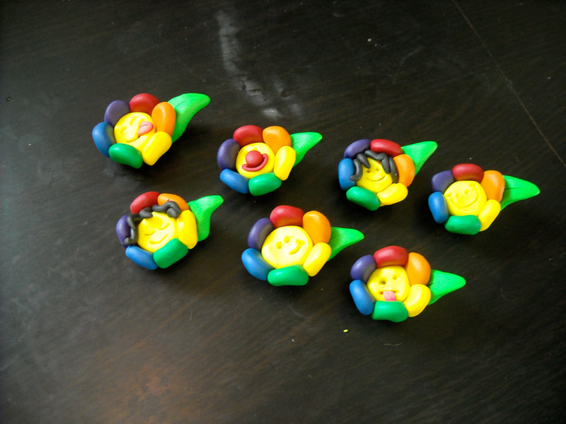 Seven rainbow flower polymer clay magnets with various expressions