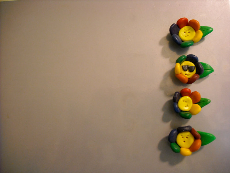 Four rainbow flower polymer clay magnets with various expressions