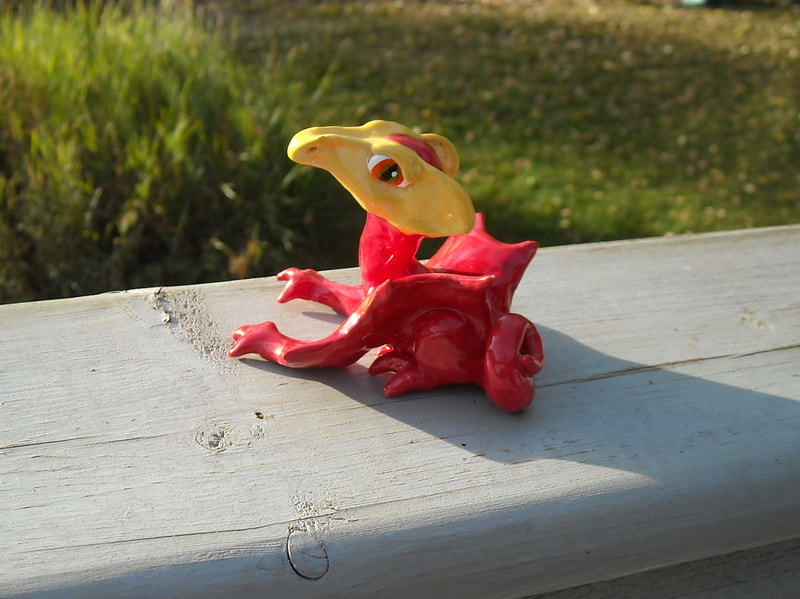 A red glazed clay dragon with a yellow face