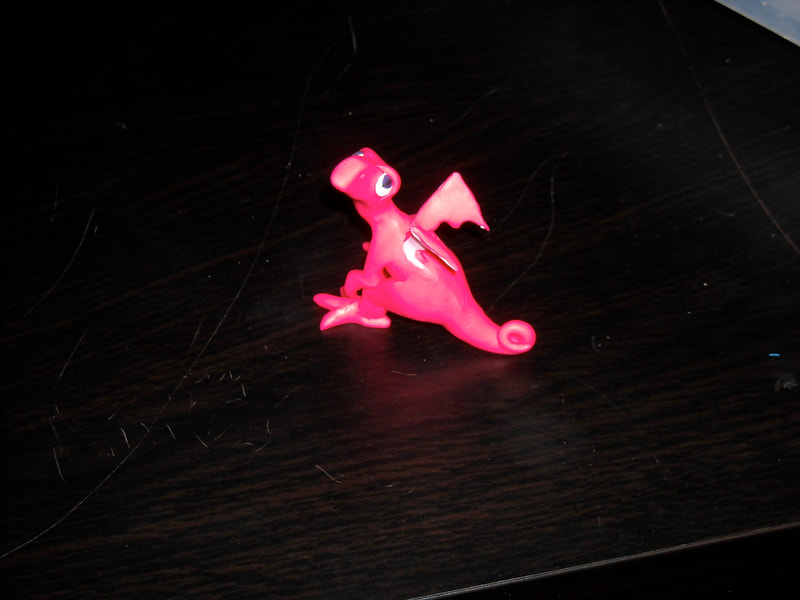 A very small hot pink polymer clay dragon
