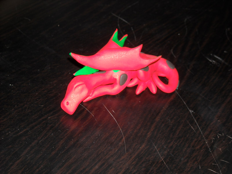 A sleeping polymer clay dragon made to look like a watermelon. 